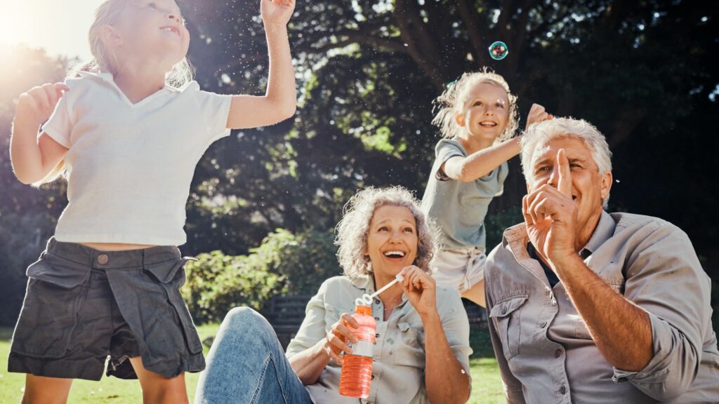 Grandparents blowing bubbles with grandkids in park