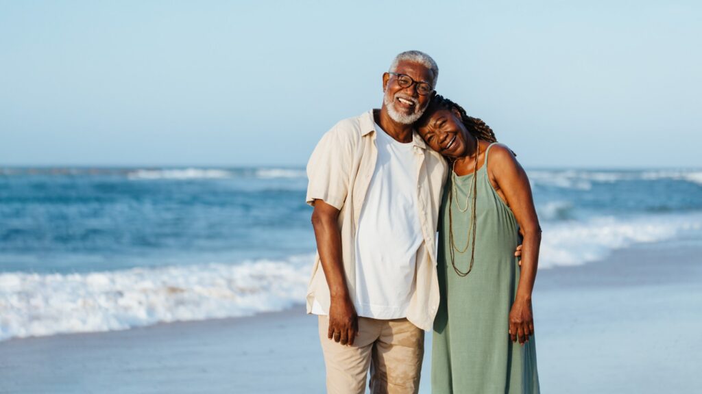 Senior African American couple embracing on beach