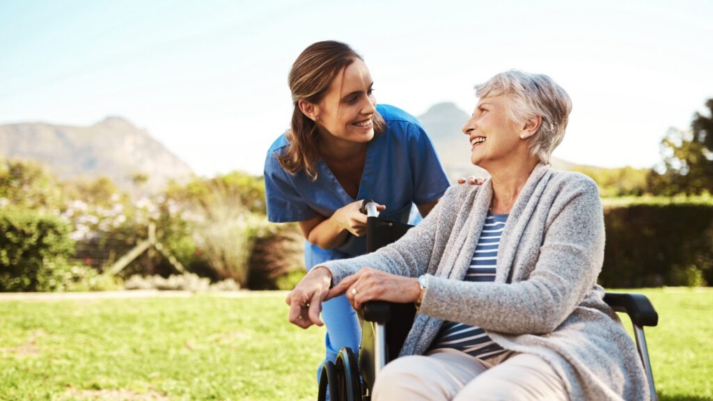 Nurse assisting senior woman in wheelchair outdoors